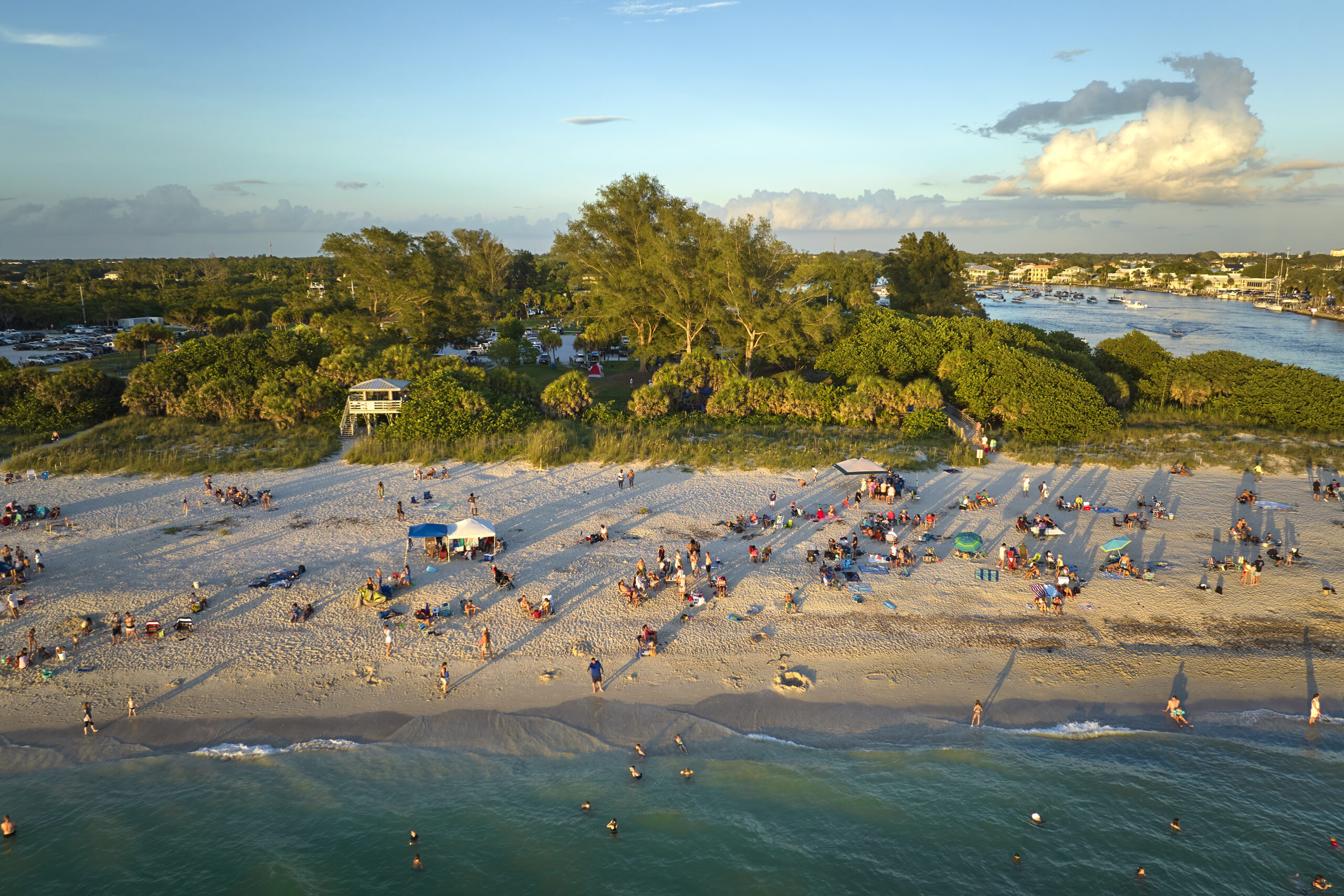 High angle view of crowded Nokomis beach in Sarasota County, USA. Many people enjoing vacations time swimming in ocean water and relaxing on warm Florida sun at sundown.